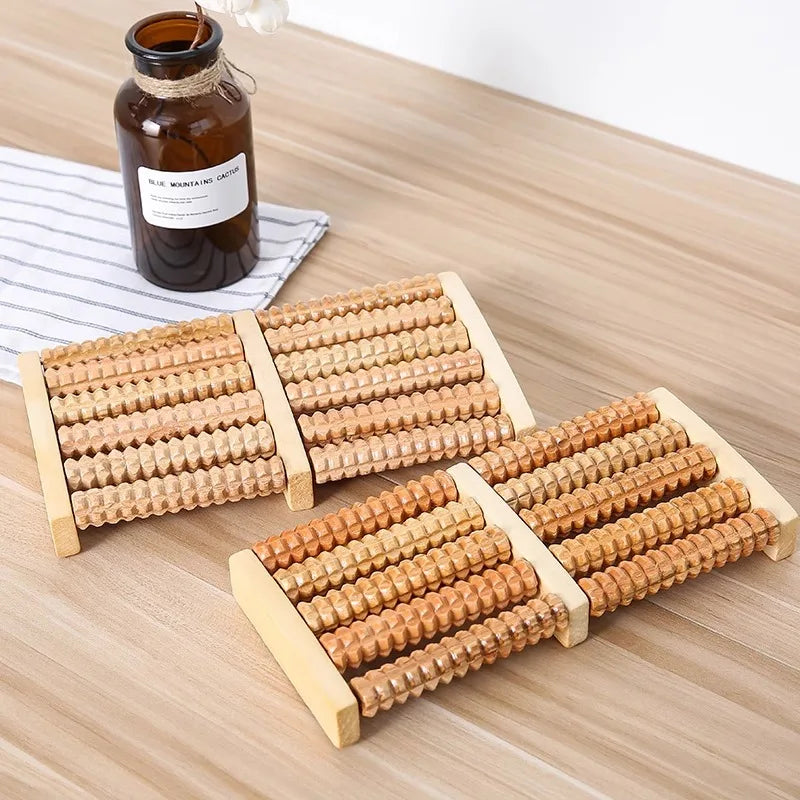 A set of wooden foot massage rollers for reflexology and tension relief resting on a light wooden surface.