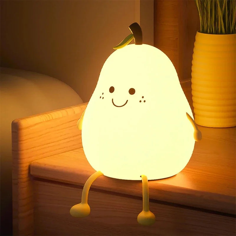 A glowing pear-shaped silicone night light rests on a wooden surface.