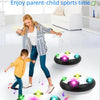 A parent and child are playing with a levitation soccer ball toy that floats on a cushion.