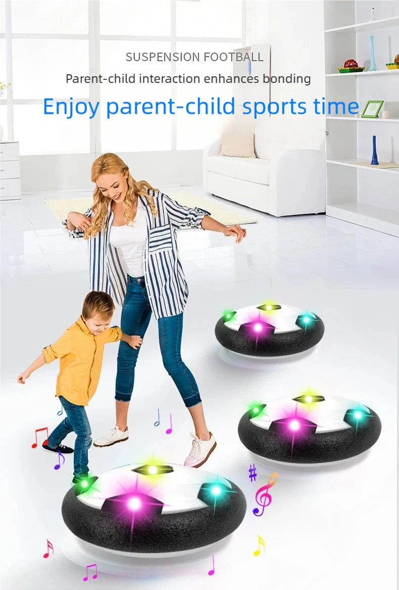A parent and child are playing with a levitation soccer ball toy that floats on a cushion.