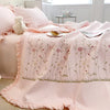 Pink quilted bedspread set with embroidered floral patterns and a fluffy white pillow