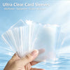 A hand holds a stack of ultra-clear plastic card sleeves for collectible cards against a light blue background.