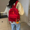 A person is wearing a bright red Japanese corduroy casual backpack over a light-colored sweater.