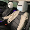 A person wearing a white ski mask head covering and a beige jacket is seated in a car seat.