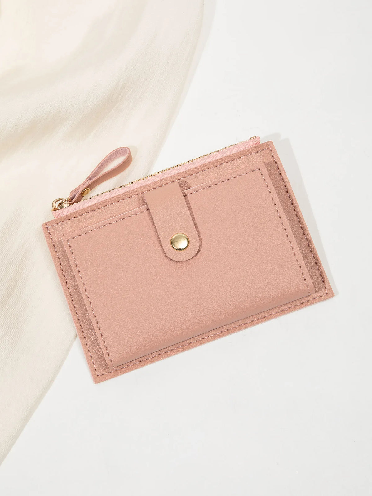 A pink women's slim PU leather card holder wallet with a stitched flap and leather pull tab.