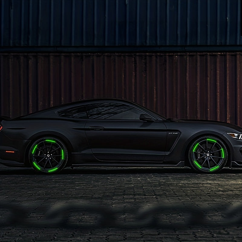 A dark gray sports car with bright green reflective wheel stickers parked on a rough ground.