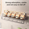 A silver wall-mounted shower caddy with gold-colored shower heads and suction cups is displayed on a light-colored wall.
