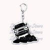 A silver metal key ring with a detailed off-road truck charm featuring a vehicle silhouette on a pile of black rocks.