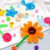 A collection of 100 chenille pipe cleaners in various colors and shapes laid out on a white cloth.