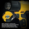 Close-up of a yellow cordless heat gun showing the safety mechanism for starting or closing work.