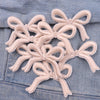 Light pink embroidered cartoon bow iron-on patches sewn onto a denim fabric.