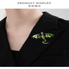 A close-up display of an enamel dragon brooch with rhinestone accents pinned on a black shirt collar.