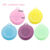 Three silicone food storage lids in random colors pink yellow blue and green with paw print designs