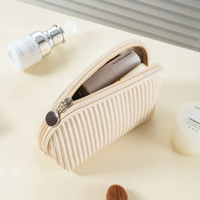 A beige PU leather makeup bag set containing a lip product and a small white tube is shown on a light surface.