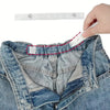 A hand is attaching an adjustable invisible belt tightener set to the waistband of blue denim jeans.