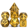 A set of seven gold metal polyhedral dice featuring a dragon font design.