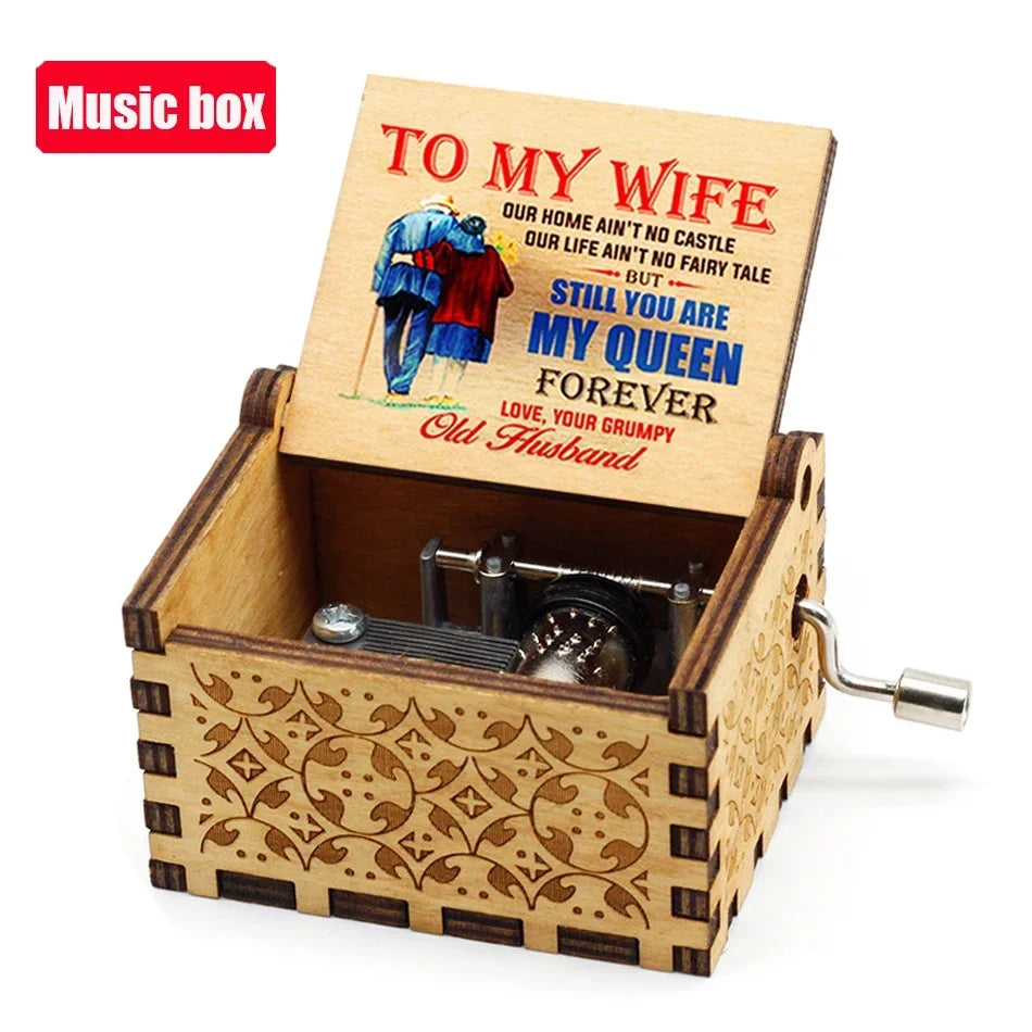A wooden music box with an engraved lid featuring text and a painted illustration of a couple.