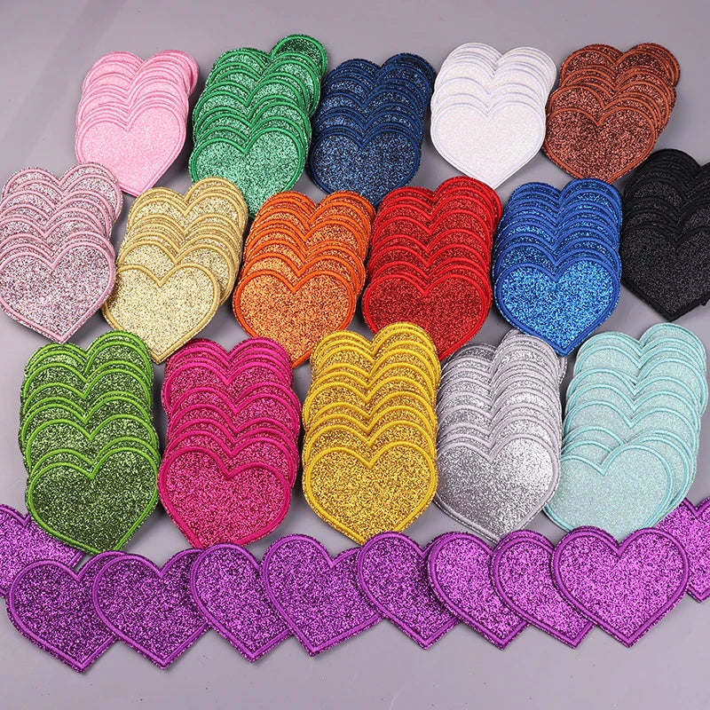 A collection of five heart-shaped iron-on embroidered patches in various glitter colors including pink, green, purple, gold, 