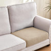 A light gray sofa slipcover featuring a beige textured cushion and visible nailhead trim.