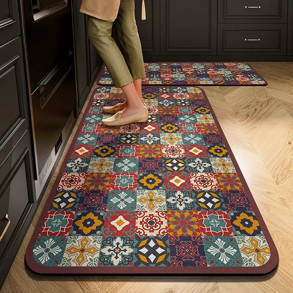 A rectangular rug with a geometric pattern in shades of red, orange, green, and blue placed on a wooden floor.