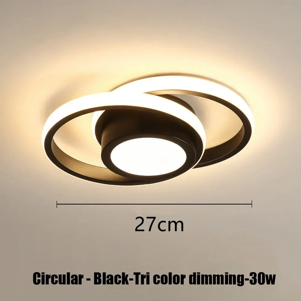 A circular black LED ceiling light fixture with a diffused glow mounted on a wall.