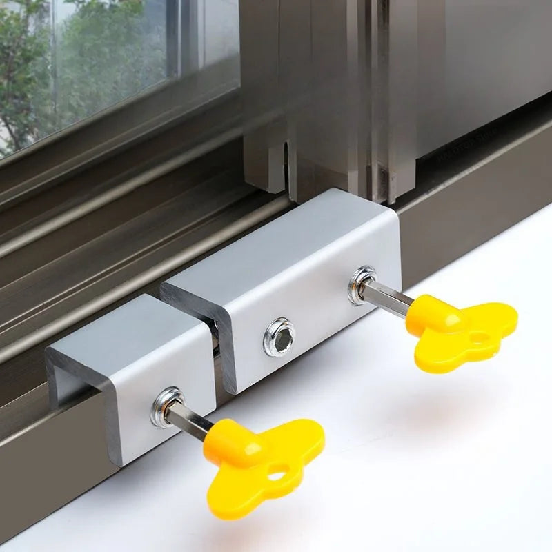 Close-up of a silver aluminum alloy sliding window lock with yellow security stoppers and hex keys installed on a window fram