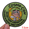 Embroidered patch featuring a cartoon character with a large head and yellow hair on a green background.