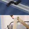 Close-up of a dark blue waterproof bag showing stitching, a zipper pull, and a tan strap detail.