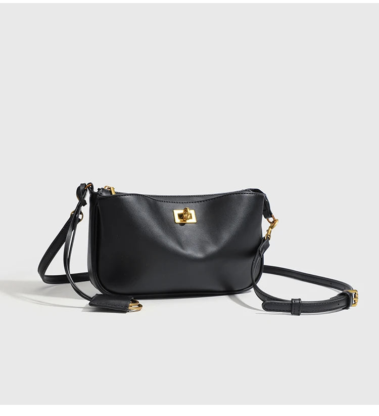 A black classic leather tote bag with a gold metal buckle shown against a light background.