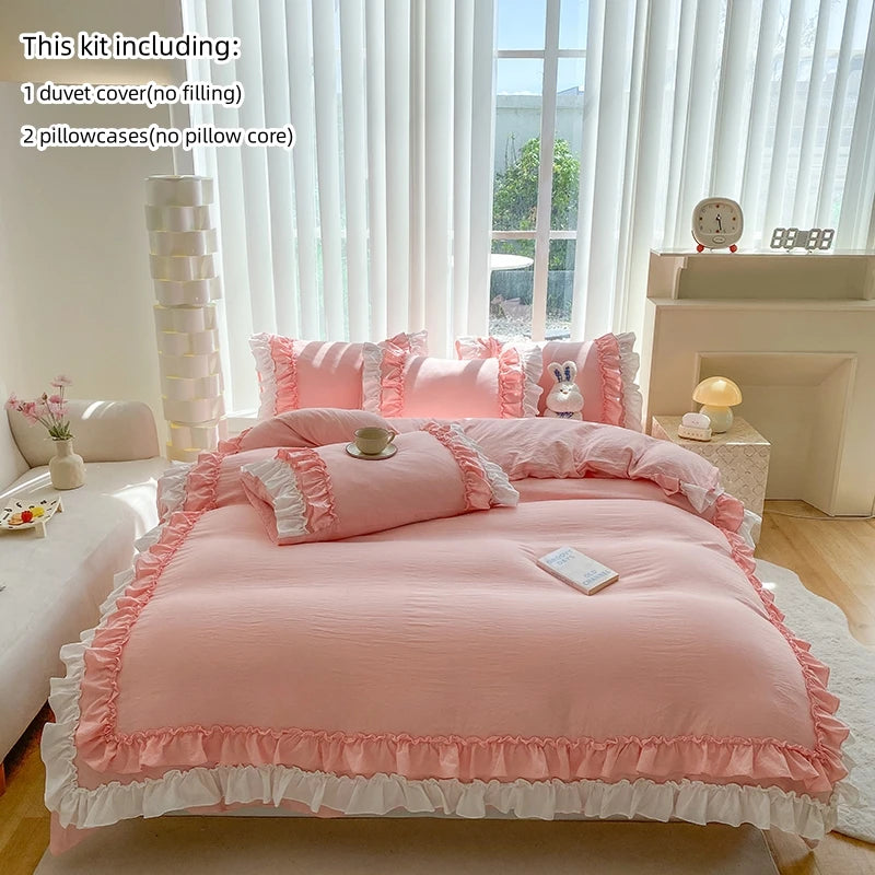 A pink duvet cover set with ruffled edges and matching pillowcases displayed on a bed in a bright room.