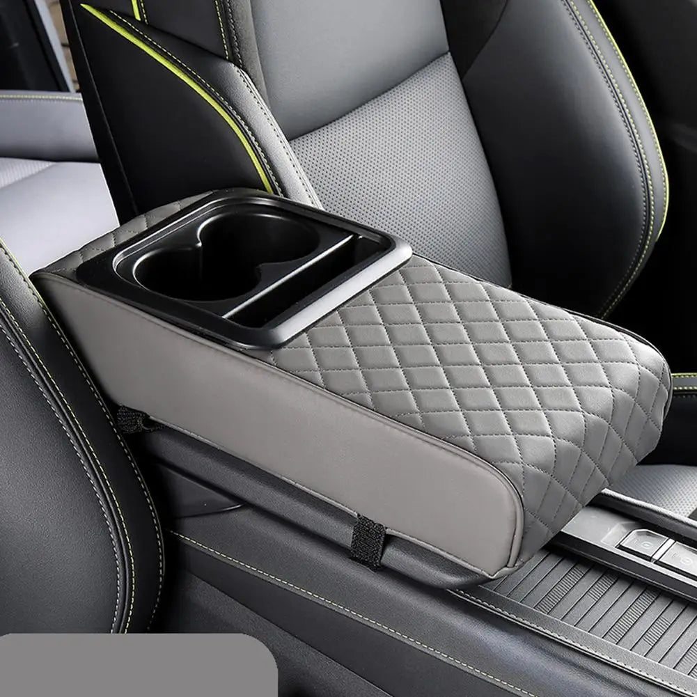 A gray quilted car center console armrest cushion with a built-in cup holder is shown in a vehicle interior.