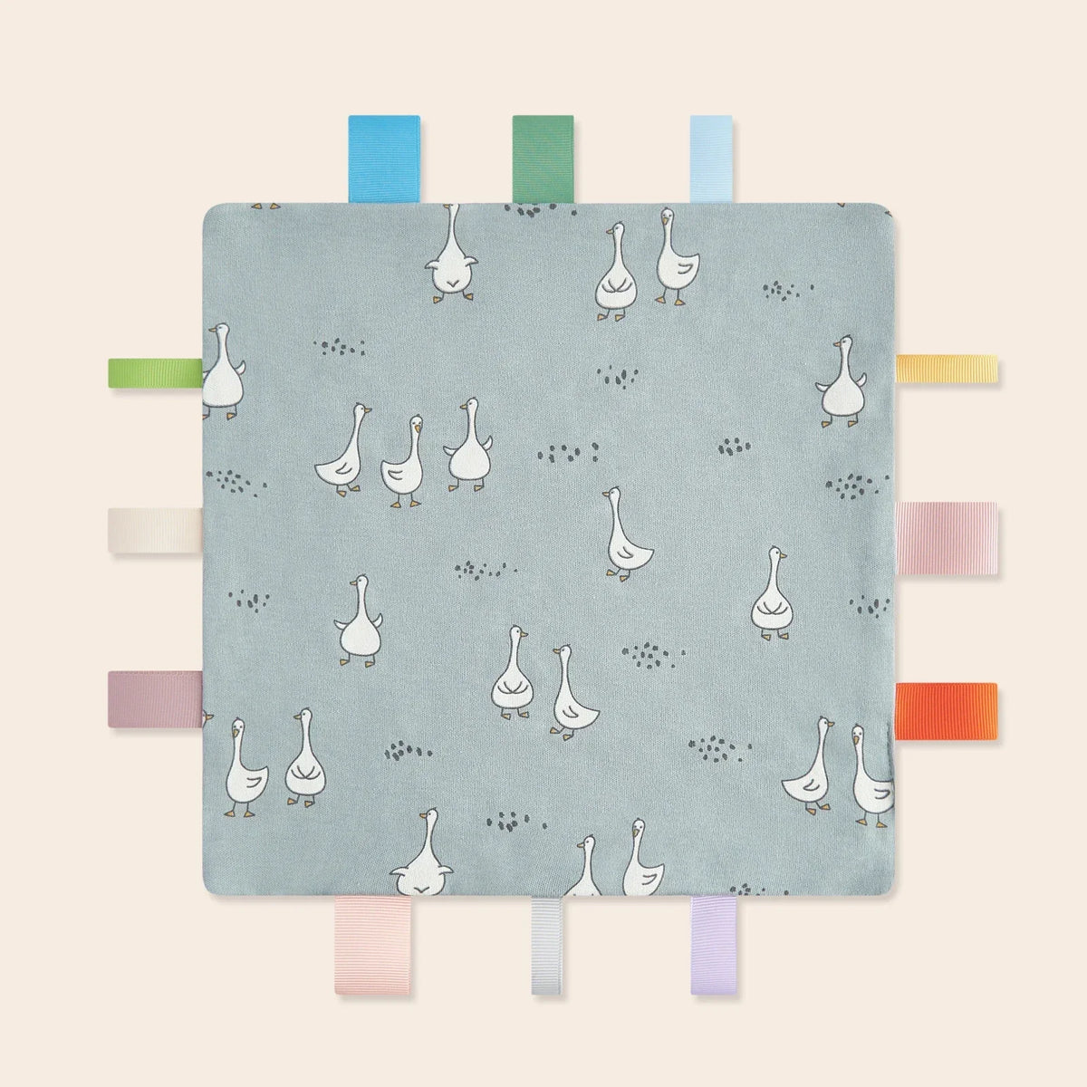 A light blue baby sensory tag comfort blanket featuring small white ducklings and various colored tags.
