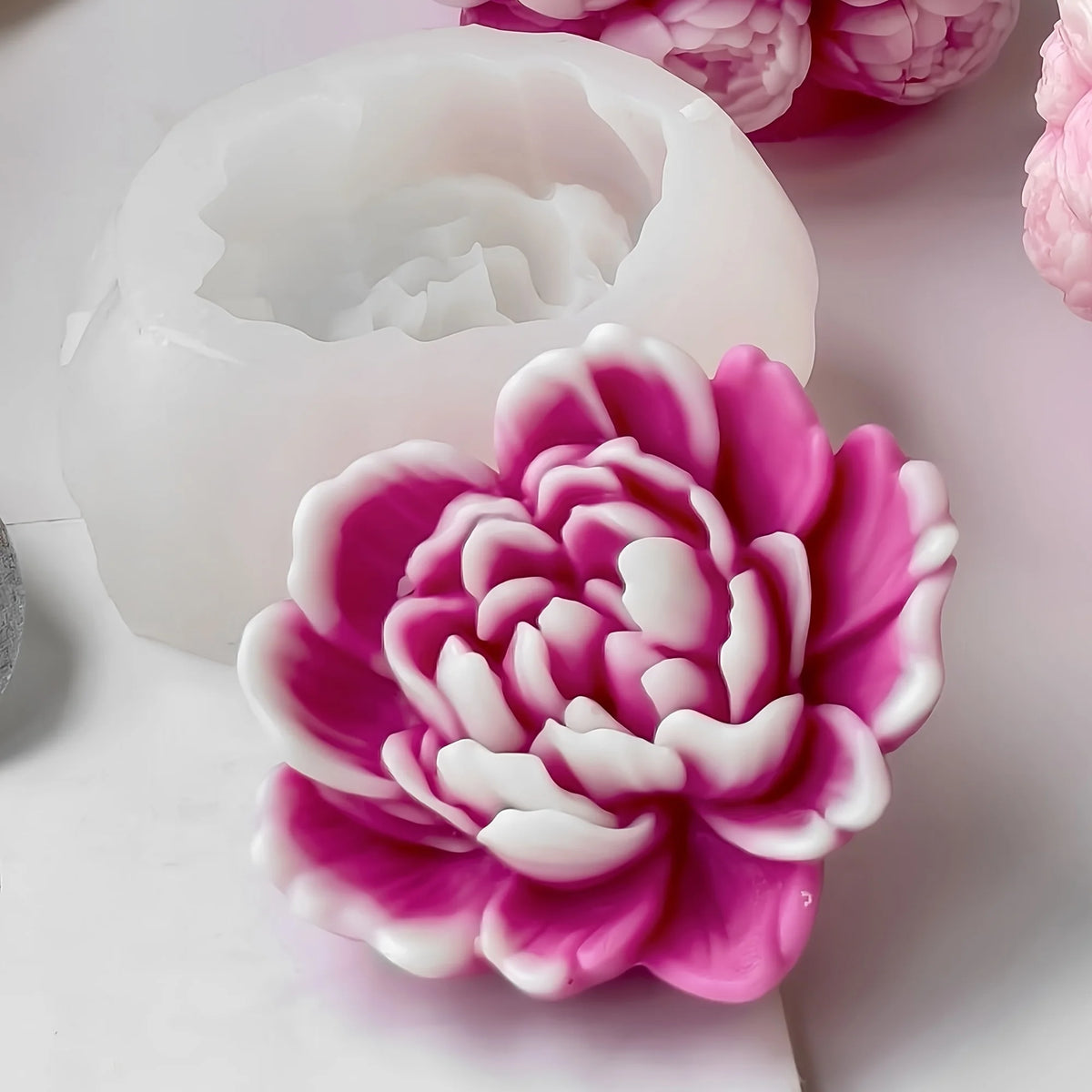 A pink and white heart flower silicone mold for crafting projects is shown next to a white wax mold.