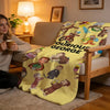 A yellow plush throw blanket featuring illustrations of various cartoon characters and animals.