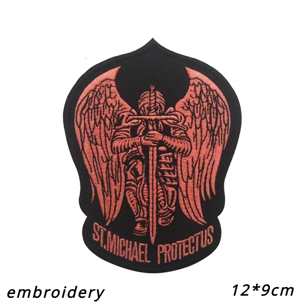A black embroidered patch featuring a stylized archangel with wings and the text St. Michael Protectus.