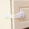 A white child safety cabinet lock is installed on a light beige cabinet door.