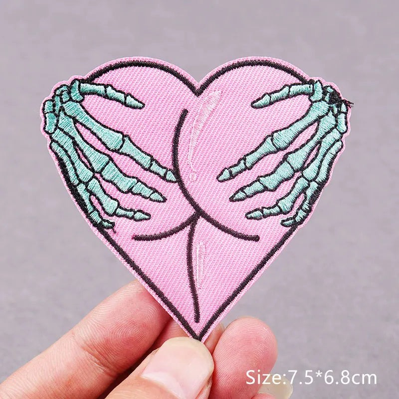 Pink heart shaped embroidered patch featuring green skeletal hands