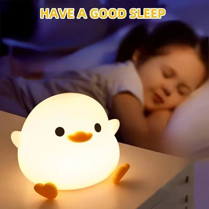 A glowing white duck night light rests on a surface next to a sleeping child.