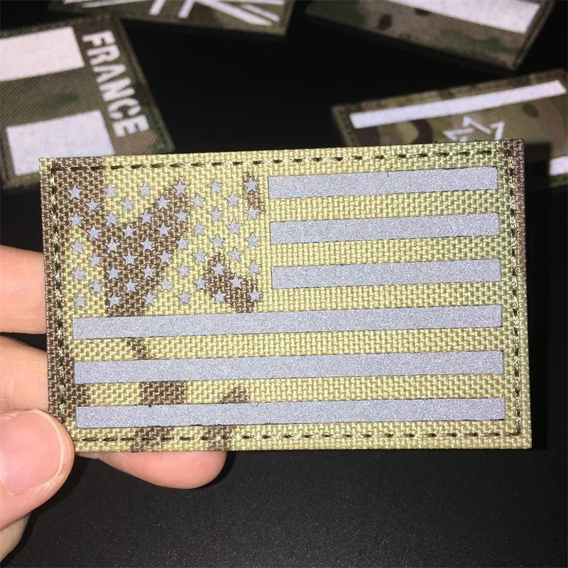 A close-up of a rectangular national flag patch featuring stars and stripes on a green fabric with a textured border.