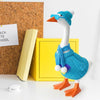A white goose statue wearing a blue knitted sweater and matching hat, standing next to a yellow box.