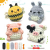 A set of crocheted animal amigurumi figures including a bee, a rabbit, and a pig, along with yarn and crochet needles.