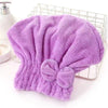 A purple microfiber hair drying towel with a bow-knot head wrap displayed in a wire basket.