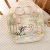 A soft cotton waterproof baby bib with an adjustable neck, featuring a woodland design and cute animal illustrations.