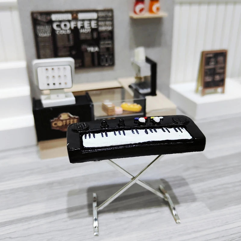 A black 1:12 scale dollhouse piano with a bench displayed on a silver stand.
