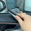 A hand is using a dual-sided microfiber scrub sponge on a car interior surface.