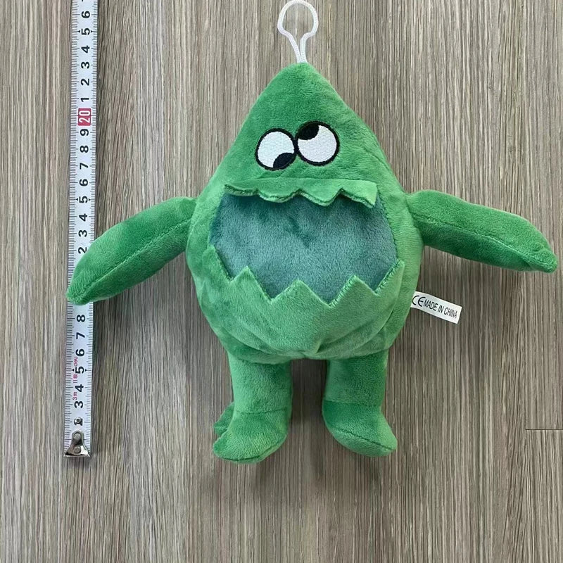 A green plush toy of an Opila Bird character is displayed next to a ruler.