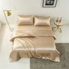 A luxurious champagne silk duvet cover set displayed on a bed with a modern gold lamp and framed art.