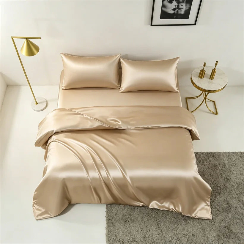A luxurious champagne silk duvet cover set displayed on a bed with a modern gold lamp and framed art.