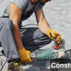 A construction worker wearing a grey shirt and pants is using a handheld power tool on a brick surface.