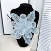 A light blue floral lace applique patch made of sequins displayed on a black mannequin.